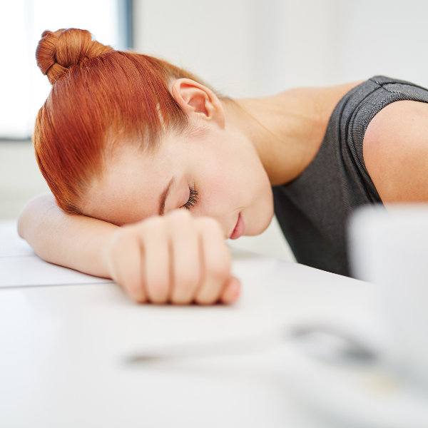woman slumped over a desk with head on one of her arms, what is a workaholic, iMind Mental Health Solutions