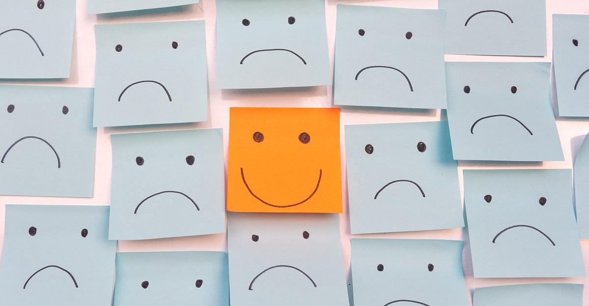 wall-of-blue-stickies-with-frowny-faces-surrounding-one-orange-sticky-with-a-happy-face-5-principles-of-positive-psychology-iMind-Mental-Health-Solutions