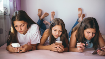 three-young-women-looking-at-phones-social-media-mental-health-teens-adolescents-iMind-Mental-Health-Solutions