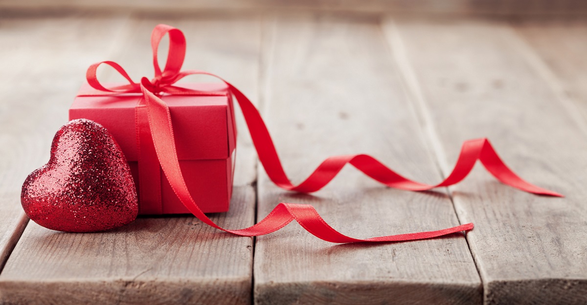 a-gift-wrapped-in-red-paper-and-a-bow-with-a-red-shiny-heart-next-to-it-on-a-wooden-table-the-psychology-of-attraction-iMind-Mental-Health-Solutions