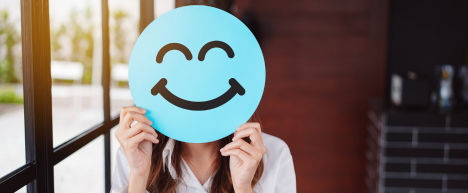 person-holding-a-paper-blue-smiley-face-over-their-own-face-the-psychology-of-attraction-iMind-Mental-Health-Solutions