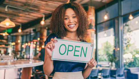 woman-entrepreneur-smiling-and-holding-an-open-sign-in-her-new-restaurant-ADHD-strengths-the-positive-side-of-ADHD-port-st-lucie-stuart-florida-iMind-Mental-Health-Solutions