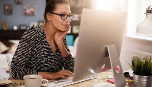 woman-sitting-at-computer-smiling-and-focused-on-her-work-ADHD-strengths-the-positive-side-of-ADHD-port-st-lucie-stuart-florida-iMind-Mental-Health-Solutions