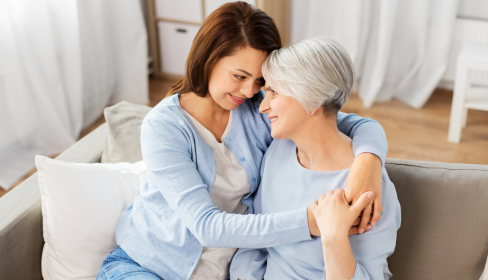 two-women-sitting-on-couch-hugging-for-support-first-mothers-day-without-mom-port-st-lucie-stuart-fl-iMind-Mental-Health-Solutions.
