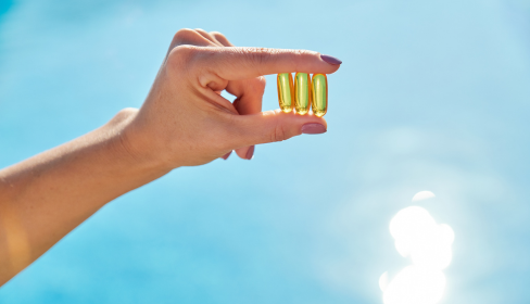 woman-holding-vitamin-D-capsules-up-toward-the-sky-how-vitamin-D-affects-mental-health-iMind-Mental-Health-Solutions.